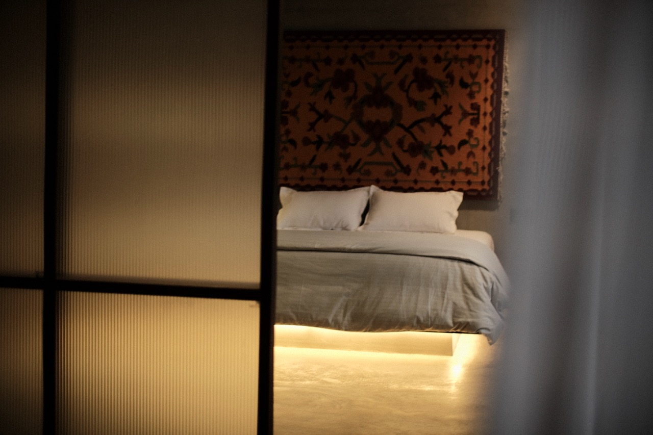The bed at night, lit softly from beneath its plinth