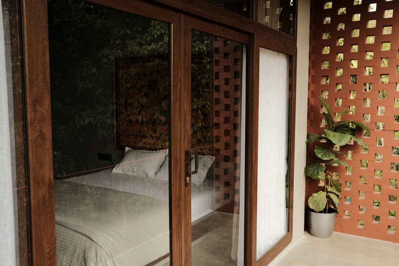 Timber sliding doors to a bedroom, a fiddle-leaf fig against the terracotta jali