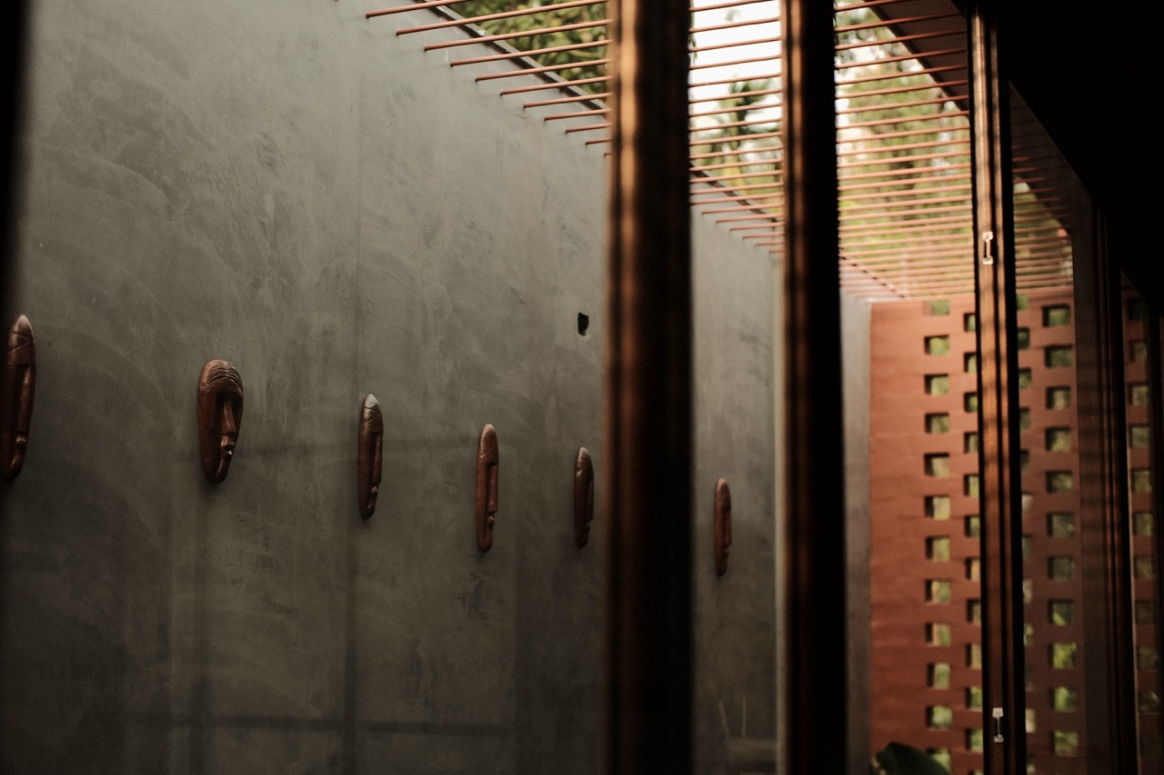 The row of carved masks with the terracotta jali screen beyond