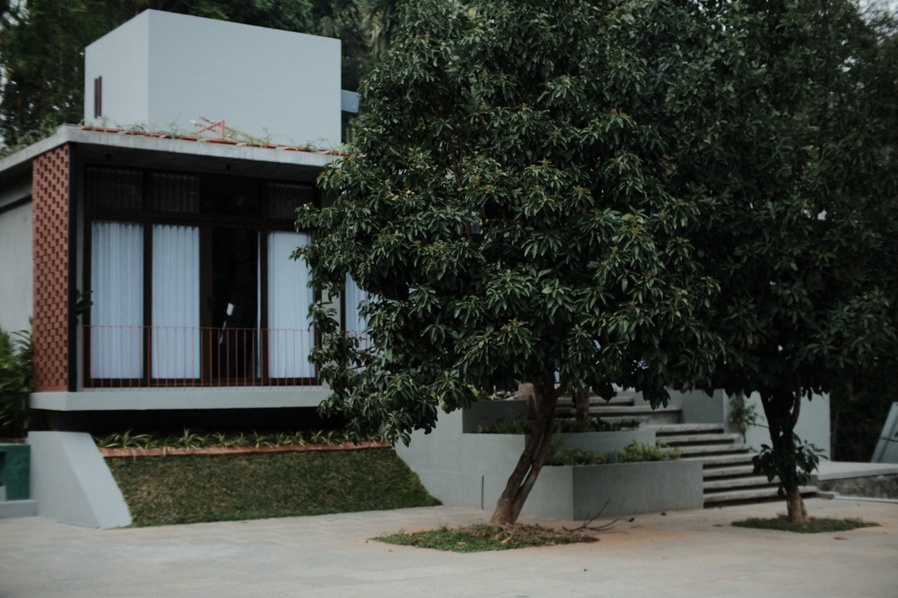 The house and courtyard with trees in the foreground at dusk