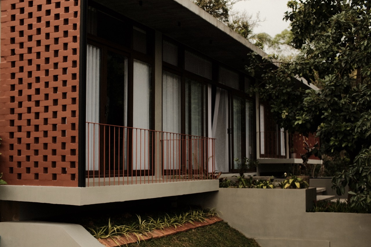 The terracotta jali screen wrapping the corner of the upper floor above a cantilevered balcony