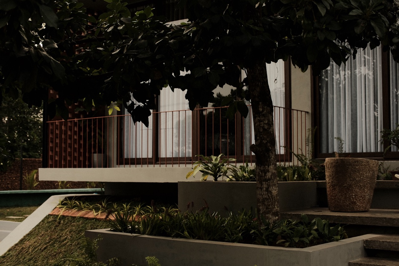 Concrete planters and a mature tree beside the verandah at dusk