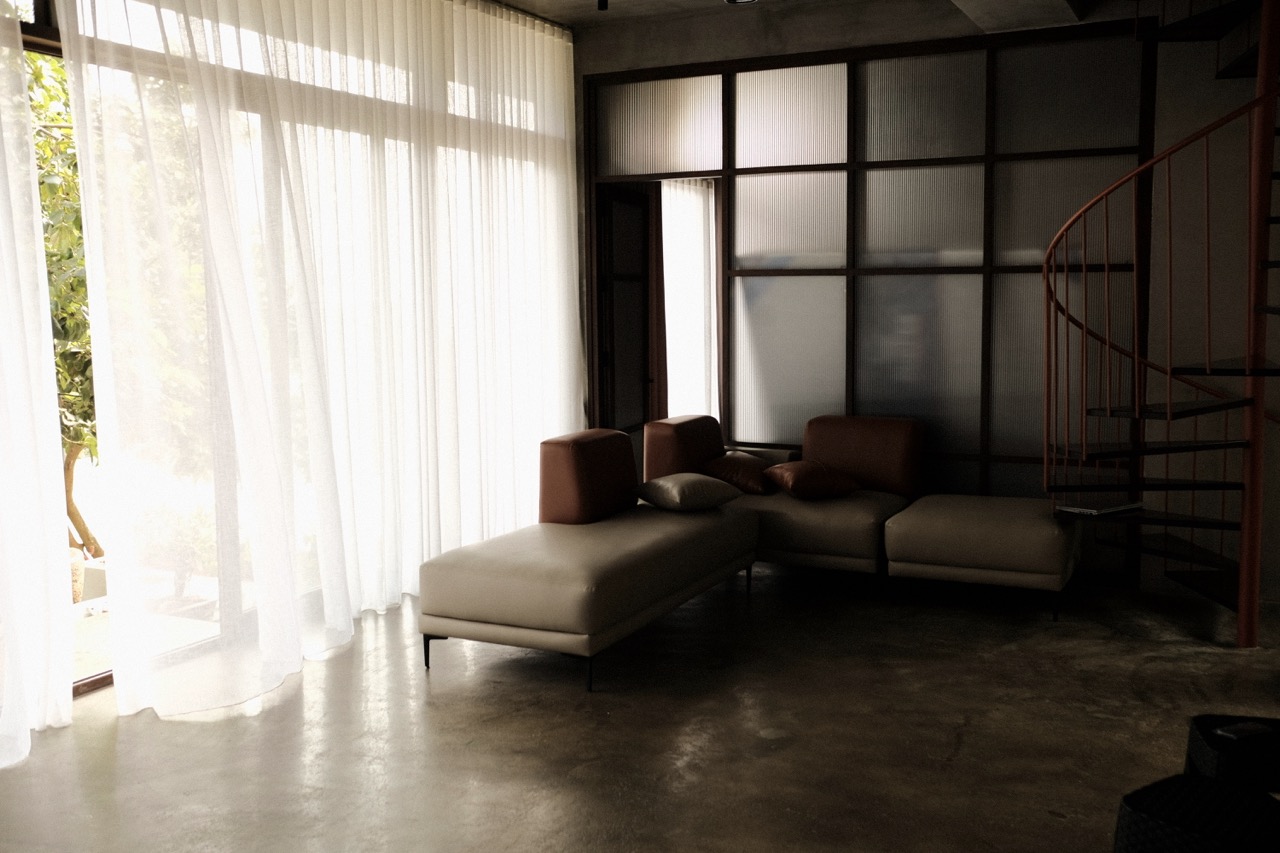 The living room with sheer curtains drawn across full-height glazing
